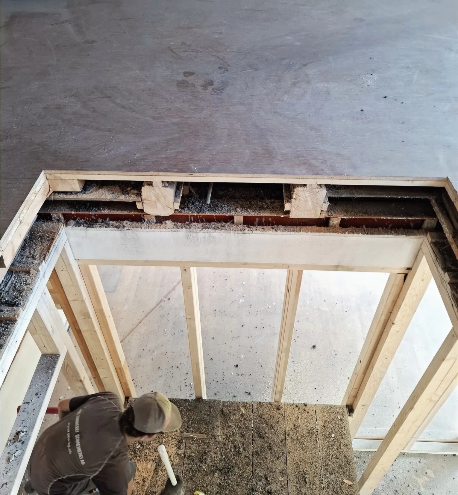 Mitarbeiter arbeitet in der Bodenöffnung für den Lift im Gemeindehaus Lupsingen, Holz-Ständerwerk