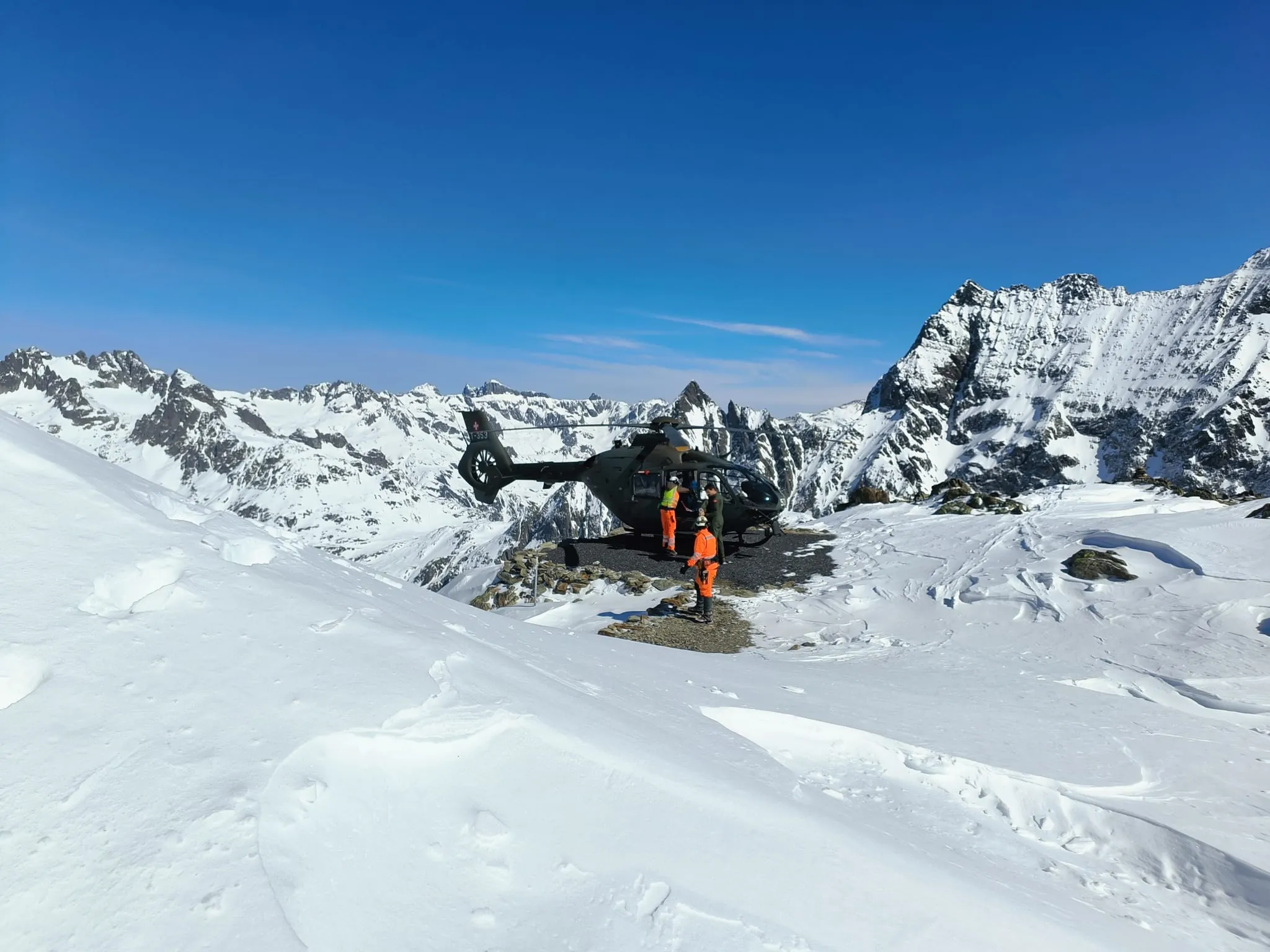 Militärhelikopter im Schnee bei der SAC-Hütte Tierbergli, Crew in Warnkleidung entlädt Material