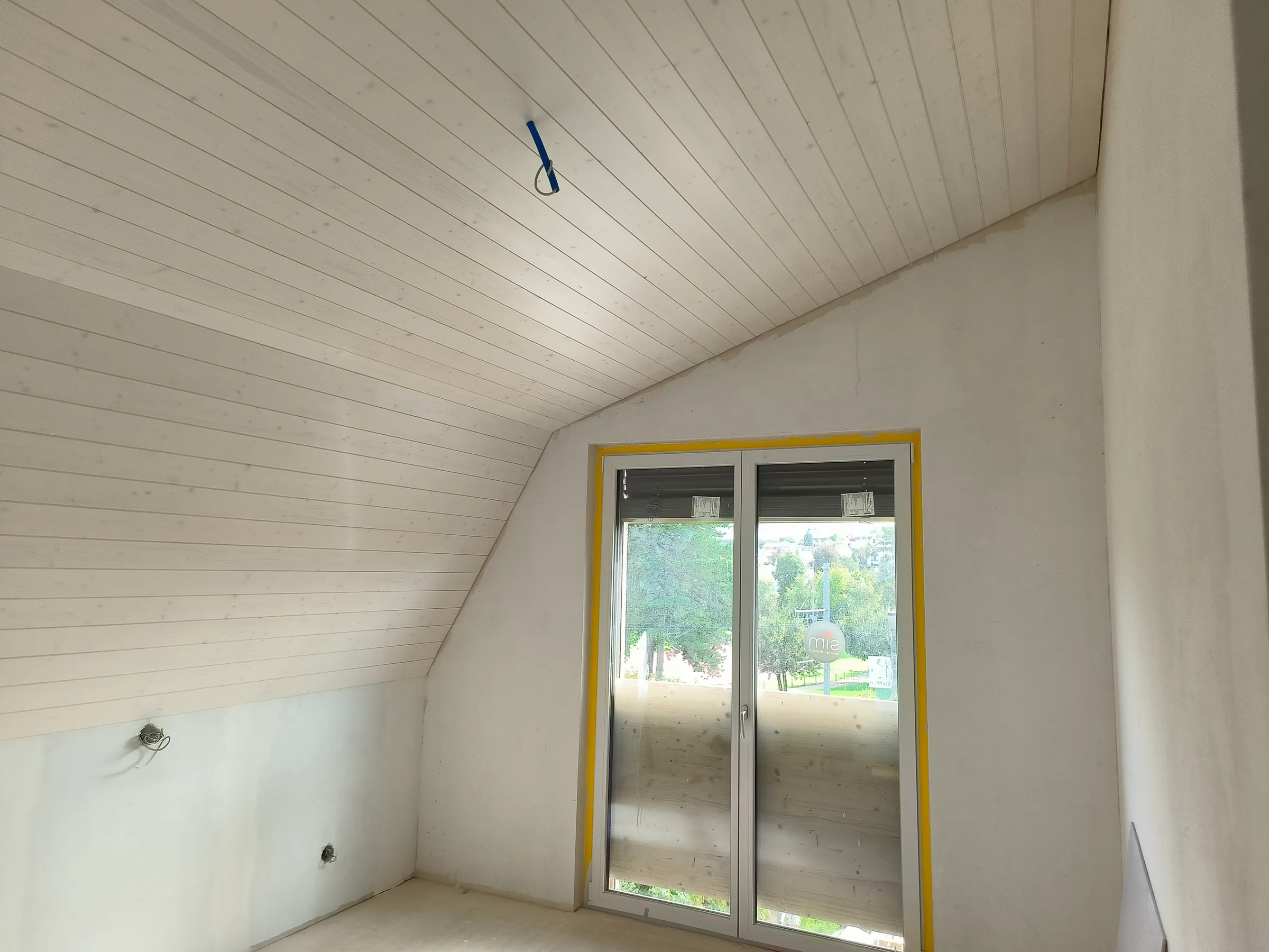 Wohnraum im Dachgeschoss des Neubaus in Therwil mit heller Holztäfer-Decke unter der Schräge