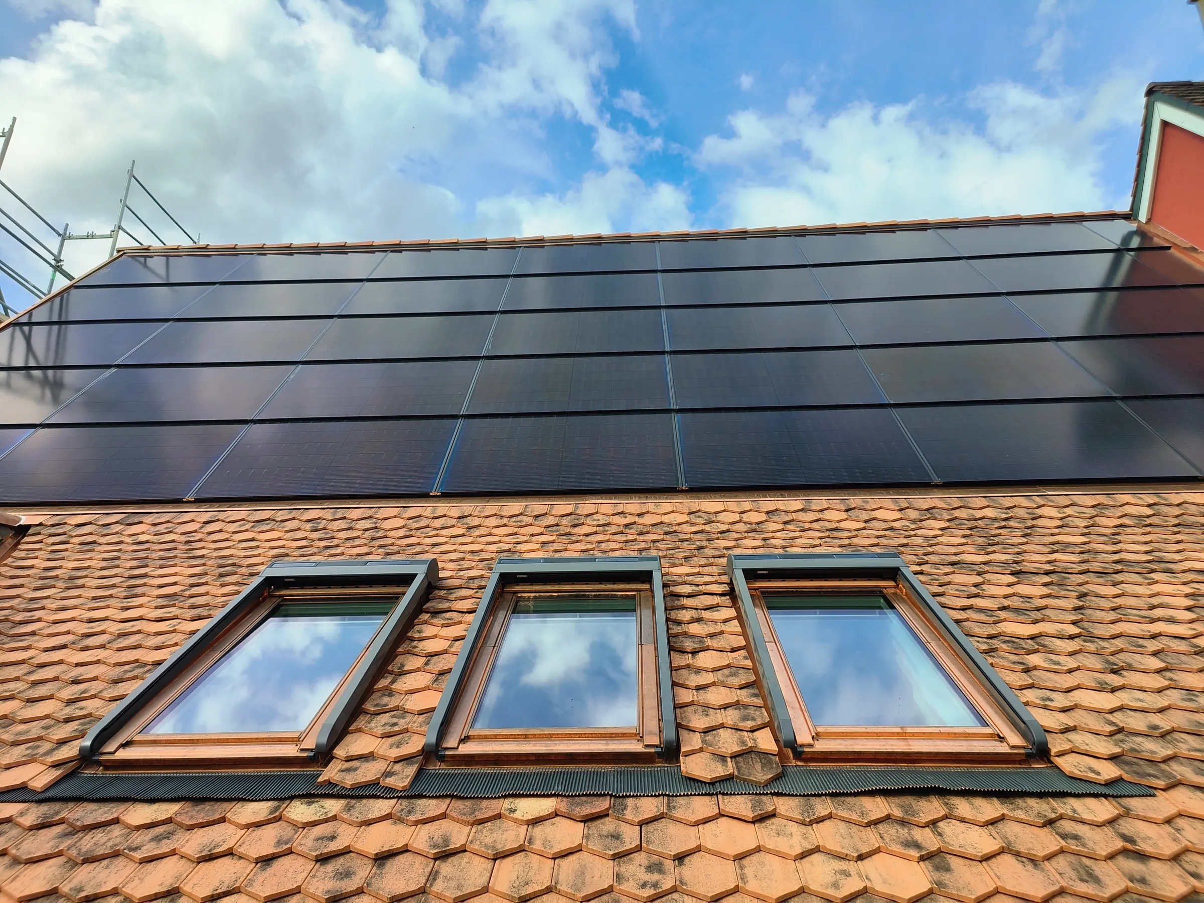Drei Velux-Dachfenster mit kupferfarbenen Eindeckrahmen im Ziegeldach unter Solarmodulen in Kaiseraugst