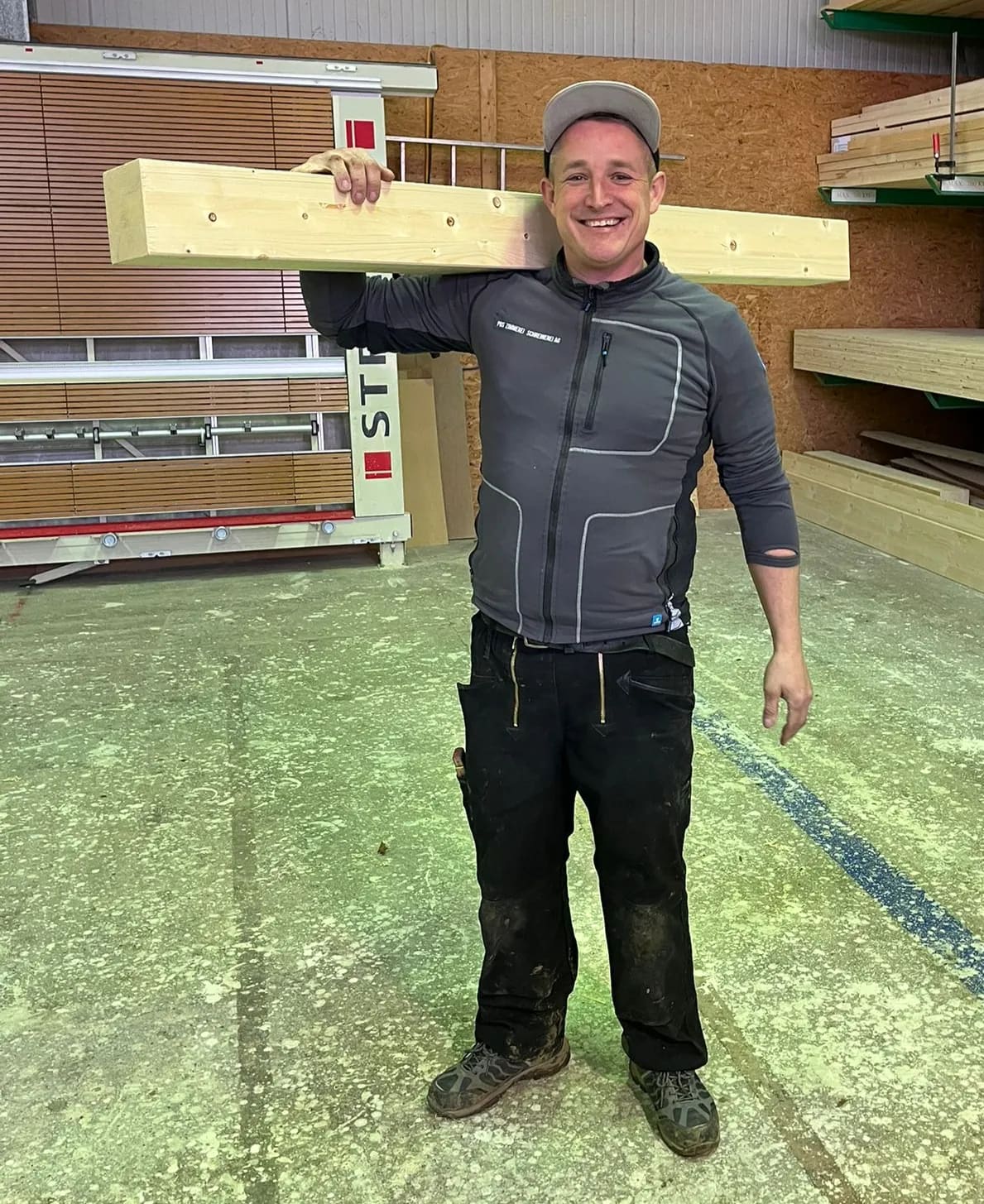 Lucas Müller, Zimmermann Vorarbeiter, trägt in der Halle ein Kantholz auf der Schulter
