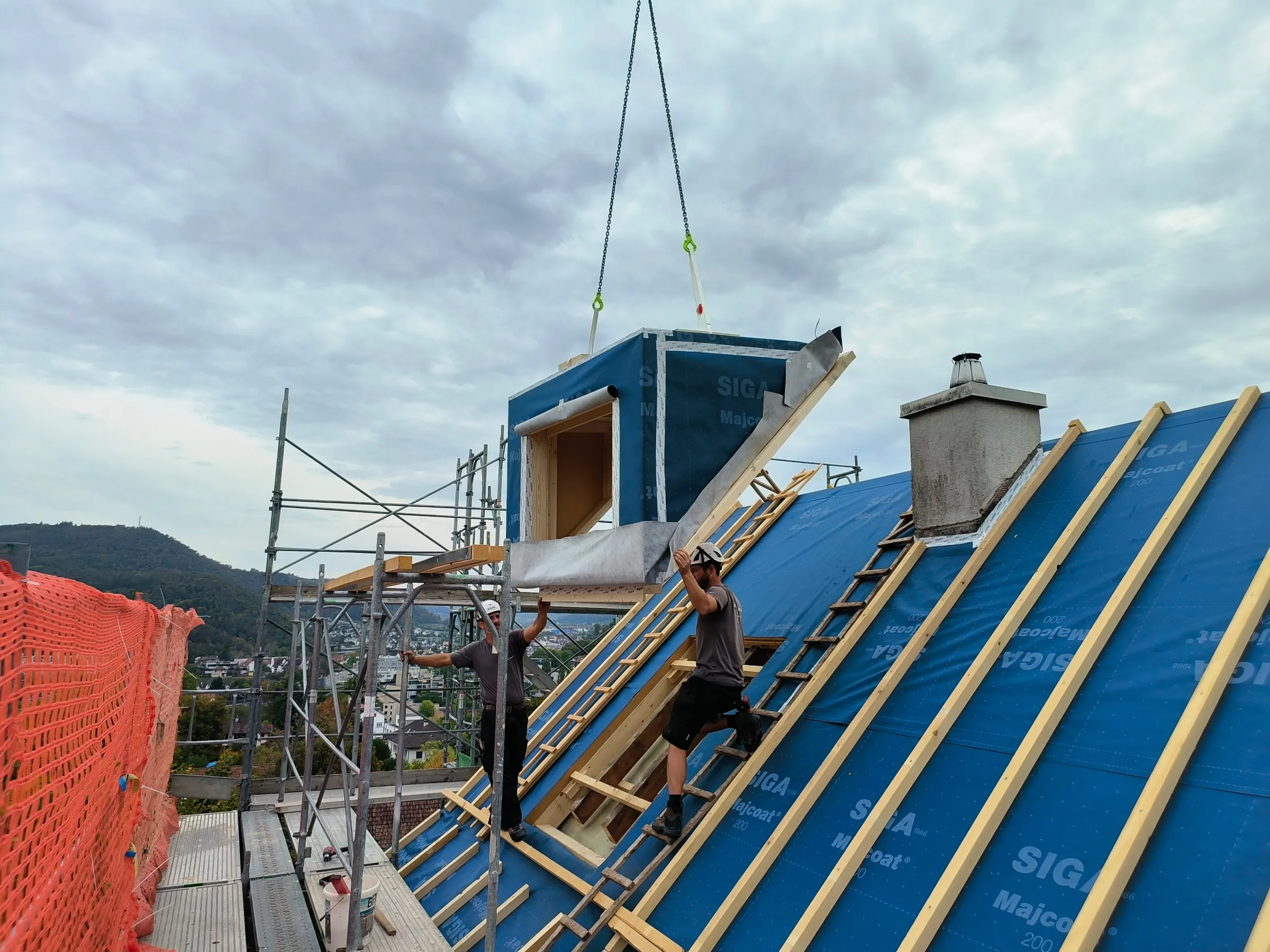 Zwei Zimmerleute führen die Gaube an ihren Platz, Liestal
