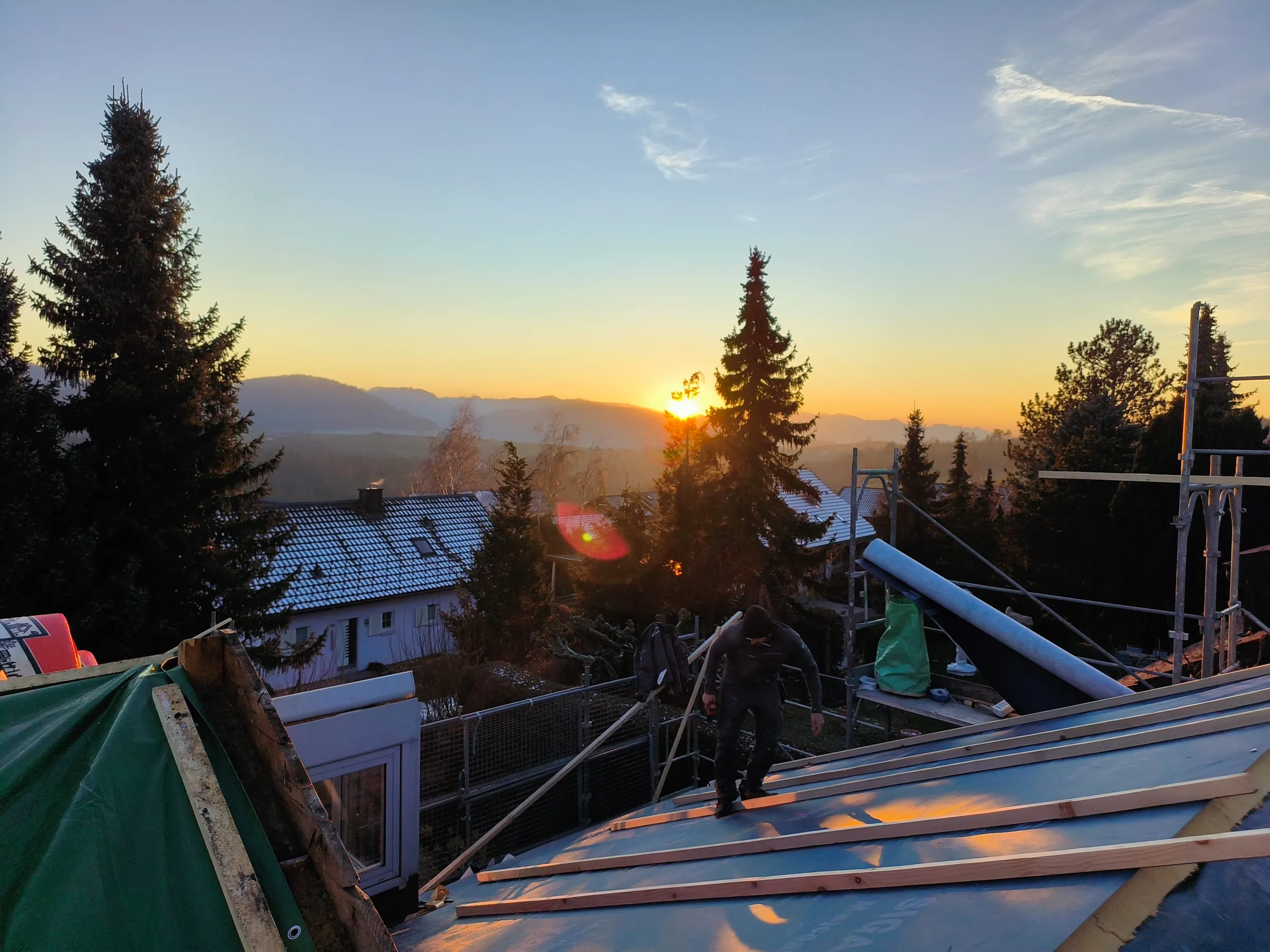 Zimmermann auf der neuen Unterdachbahn mit Lattung bei Sonnenuntergang, Dachsanierung in Rünenberg