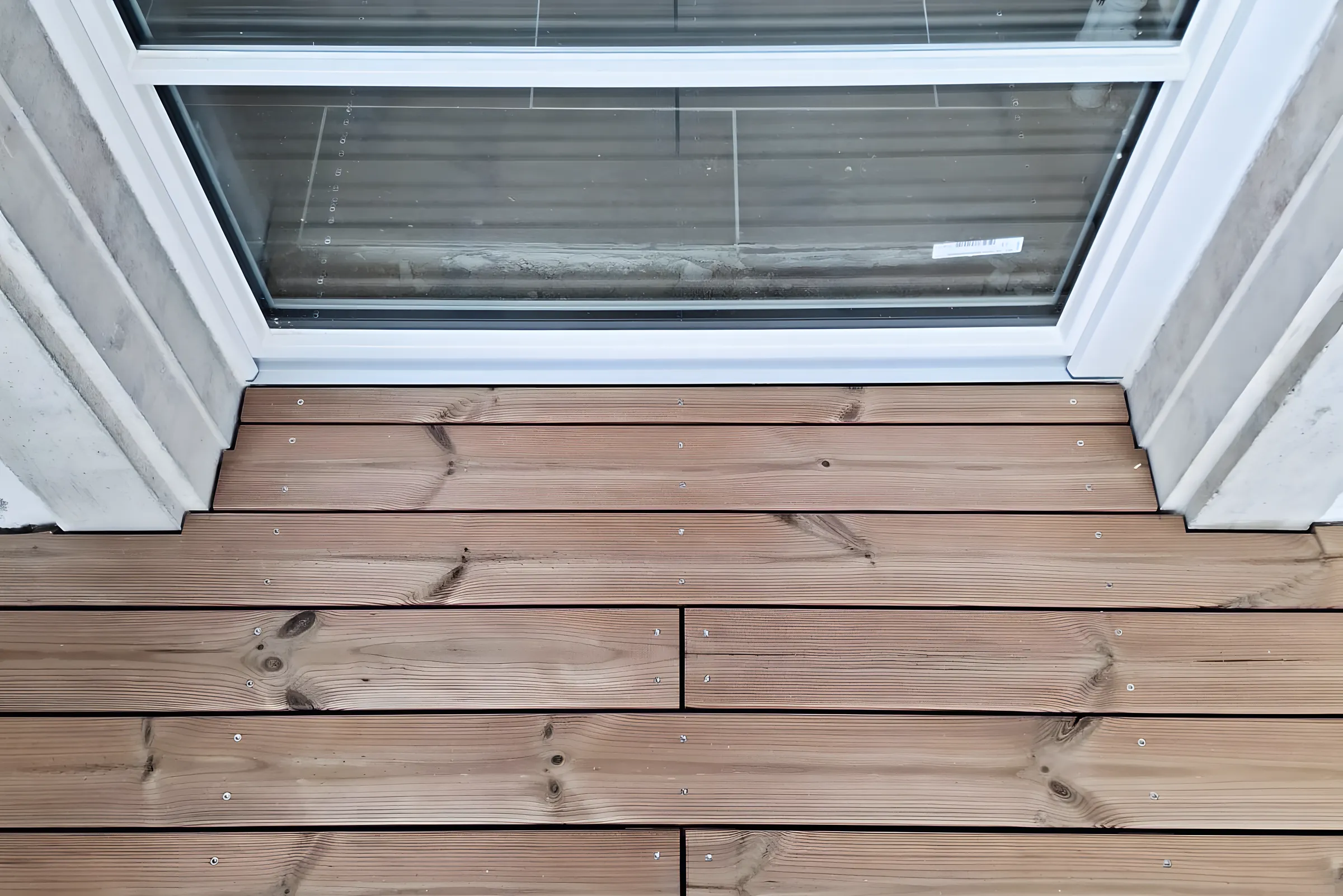 Terrassendielen aus Holz vor einer Fenstertür im Eingangsbereich, Detail