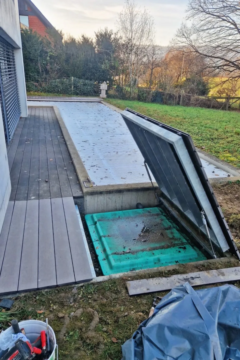 Pooldeck aus Holz im Garten mit geöffneter Falltür zum Technikschacht