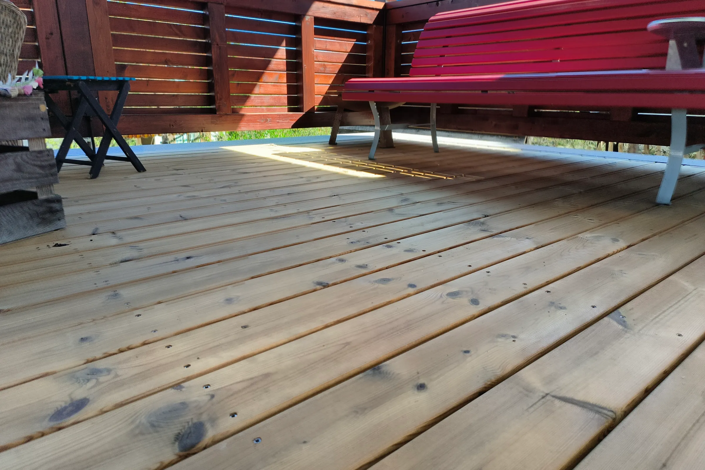 Sitzplatz mit Terrassendielen aus Thermokiefer, rote Sitzbank und Sichtschutzwand