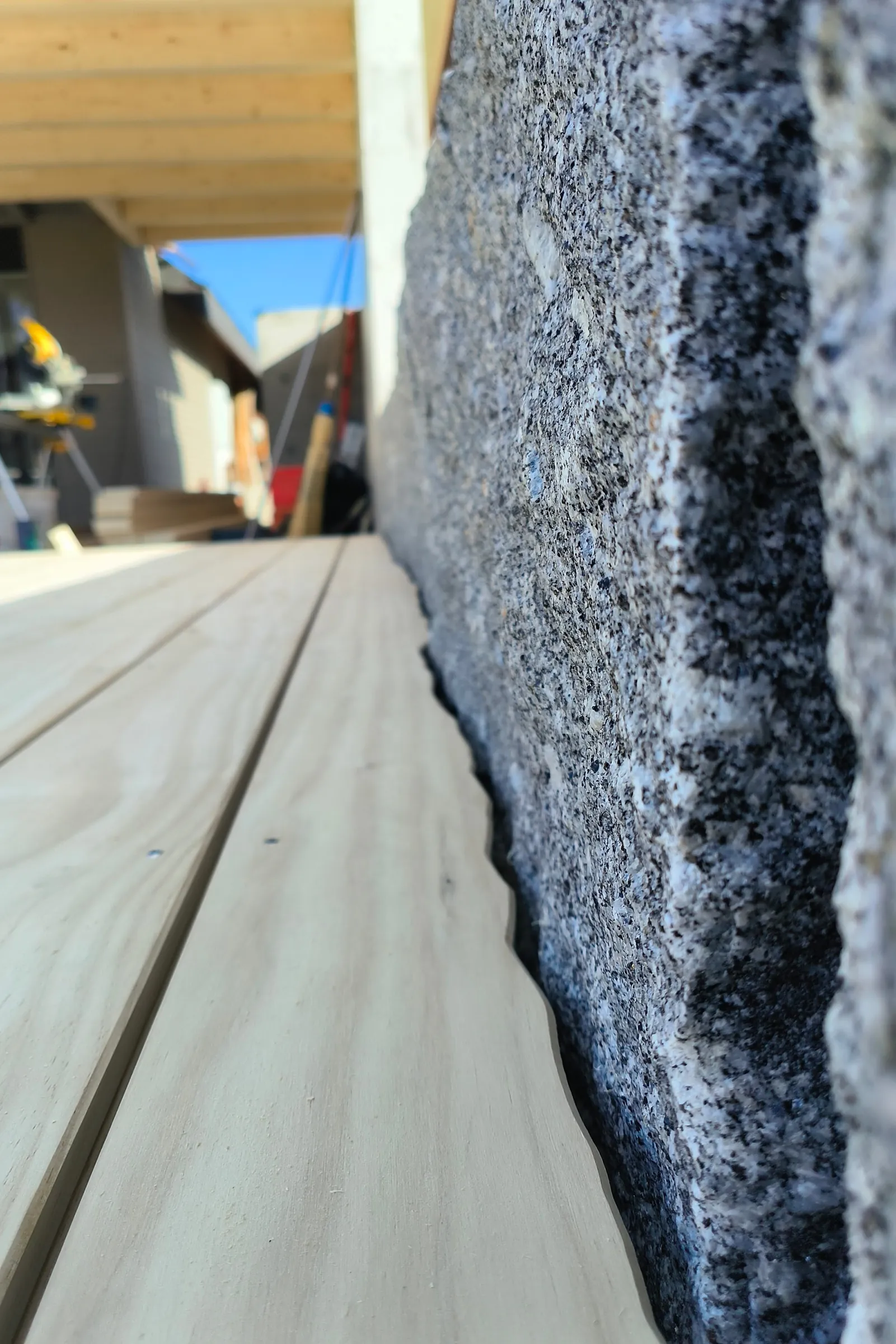 Holzdiele exakt an eine unebene Natursteinmauer angepasst, Nahaufnahme