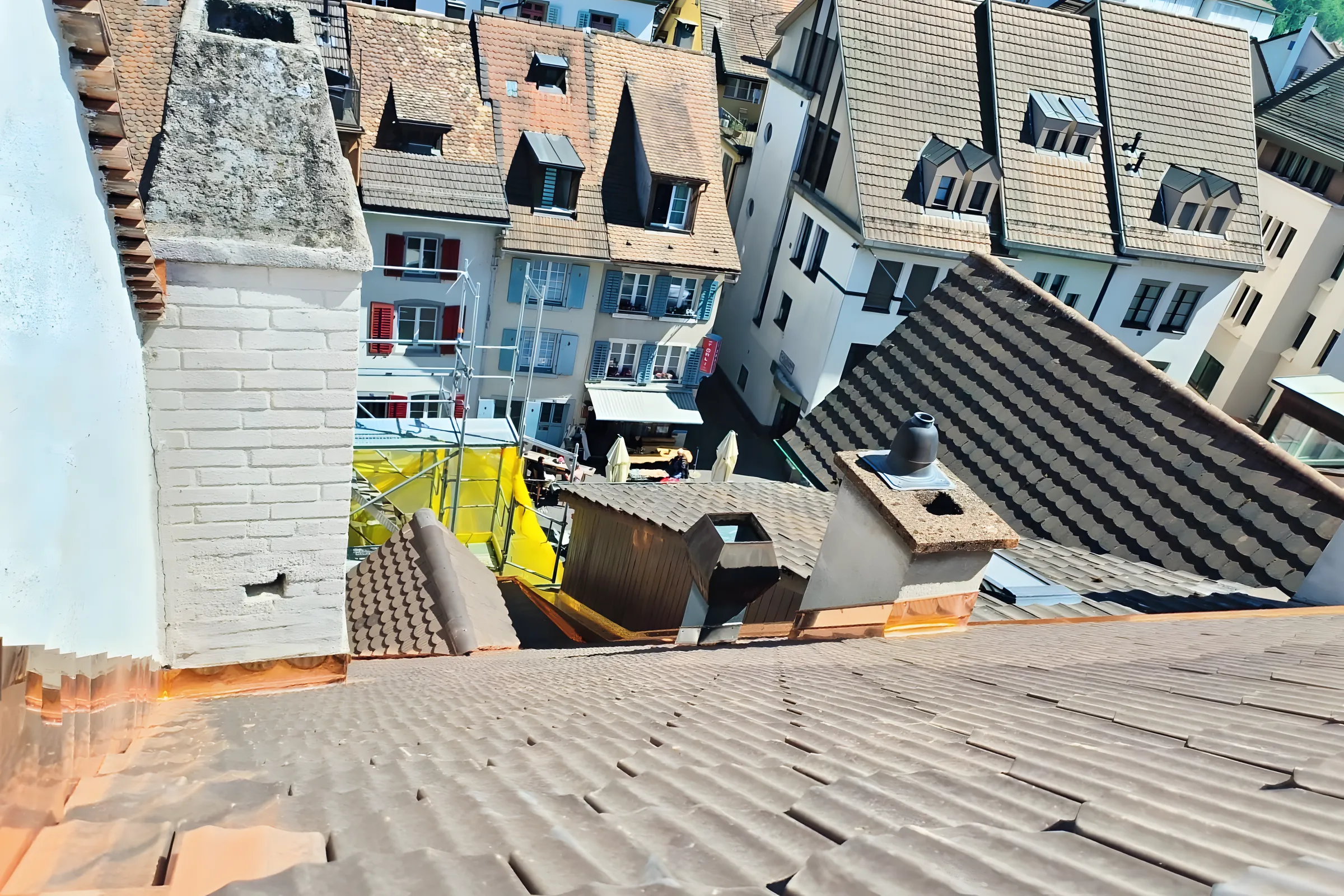 Fertig eingedecktes Biberschwanzdach mit Kupferanschlüssen an den Kaminen über der Altstadt von Liestal
