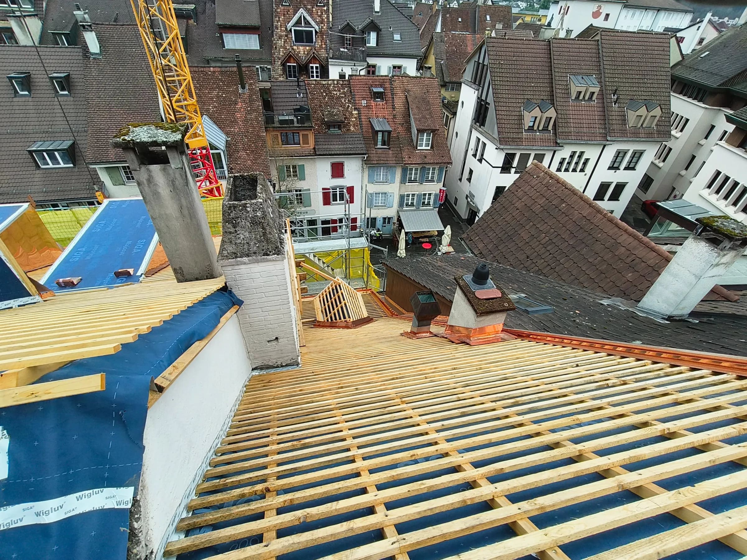 Frische Dachlattung auf dem Unterdach zwischen alten Kaminen, dahinter die Dächer der Altstadt von Liestal