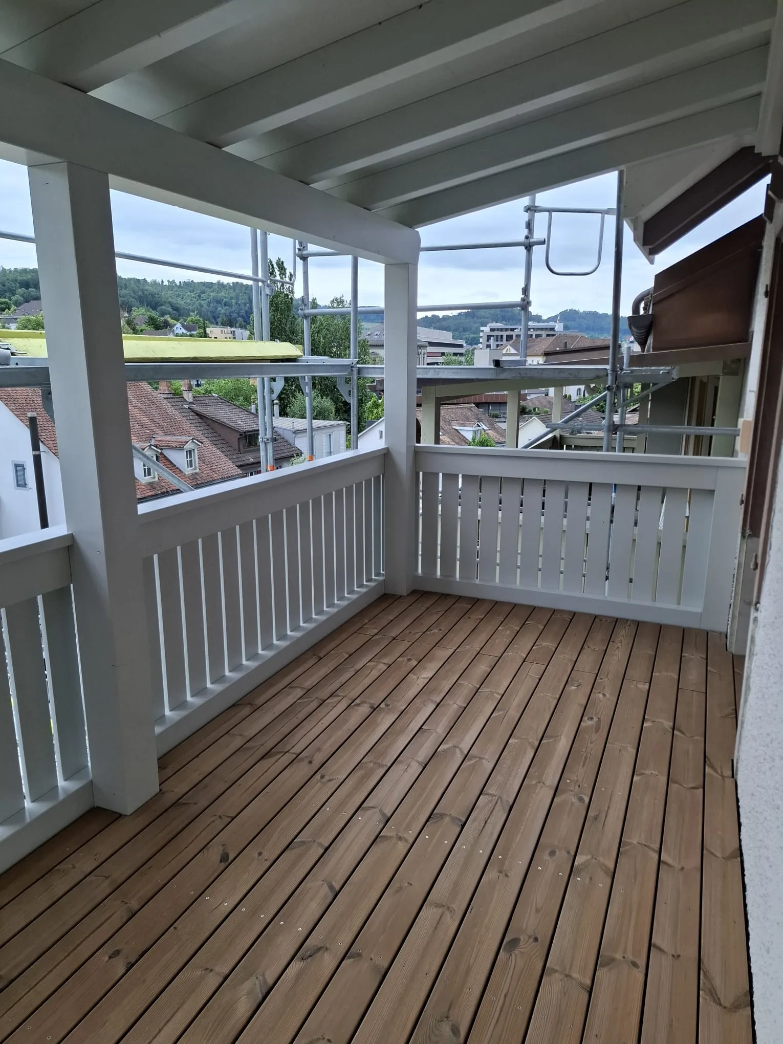 Obere Laube mit Holzboden und weissem Geländer, Blick über die Dächer von Liestal