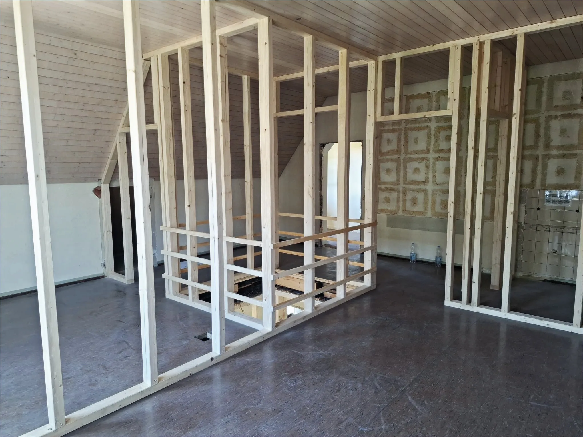 Neue, noch unbeplankte Holz-Ständerwände unter dem Dach des Gemeindehauses Lupsingen