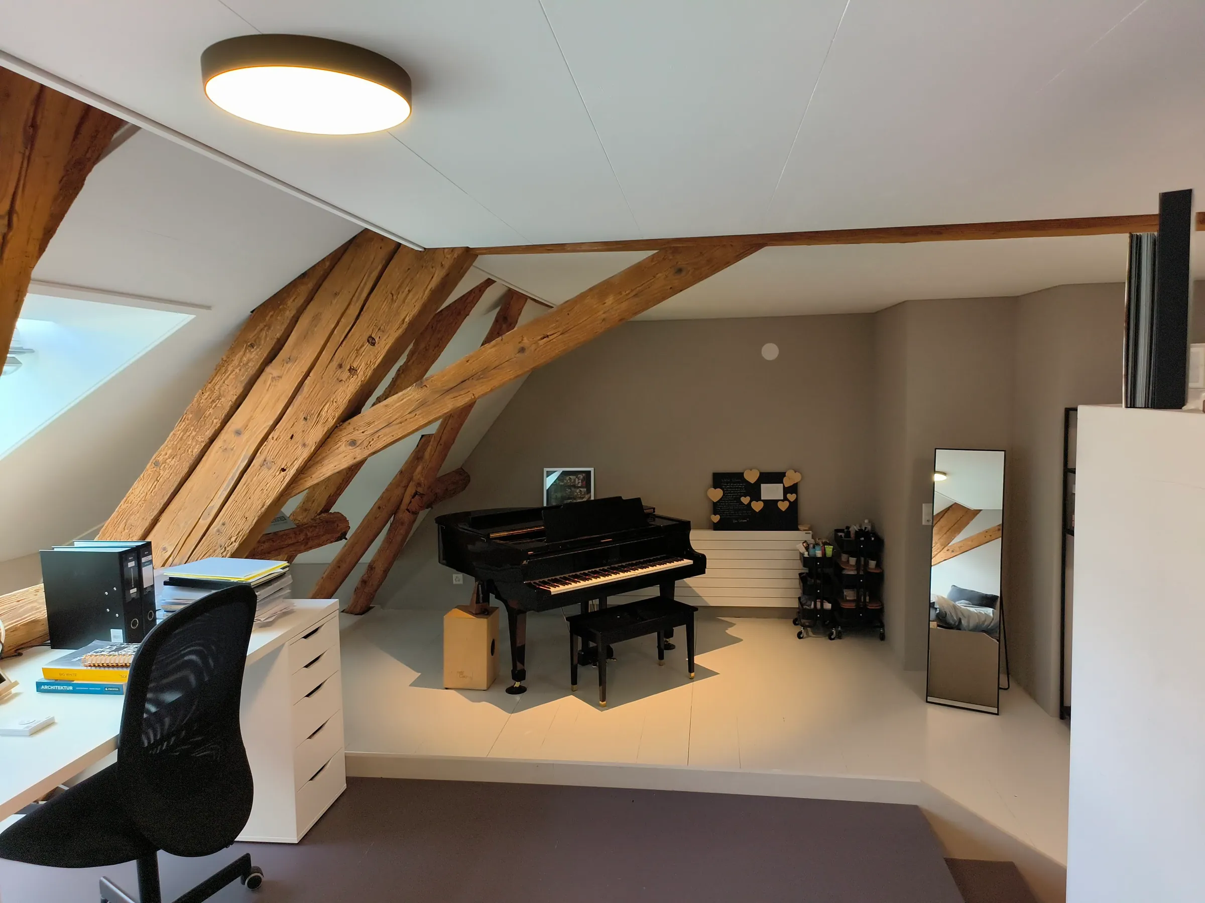 Ausgebauter Dachraum als Schlafzimmer mit sichtbarer alter Holzkonstruktion, Flügel und Dachfenster