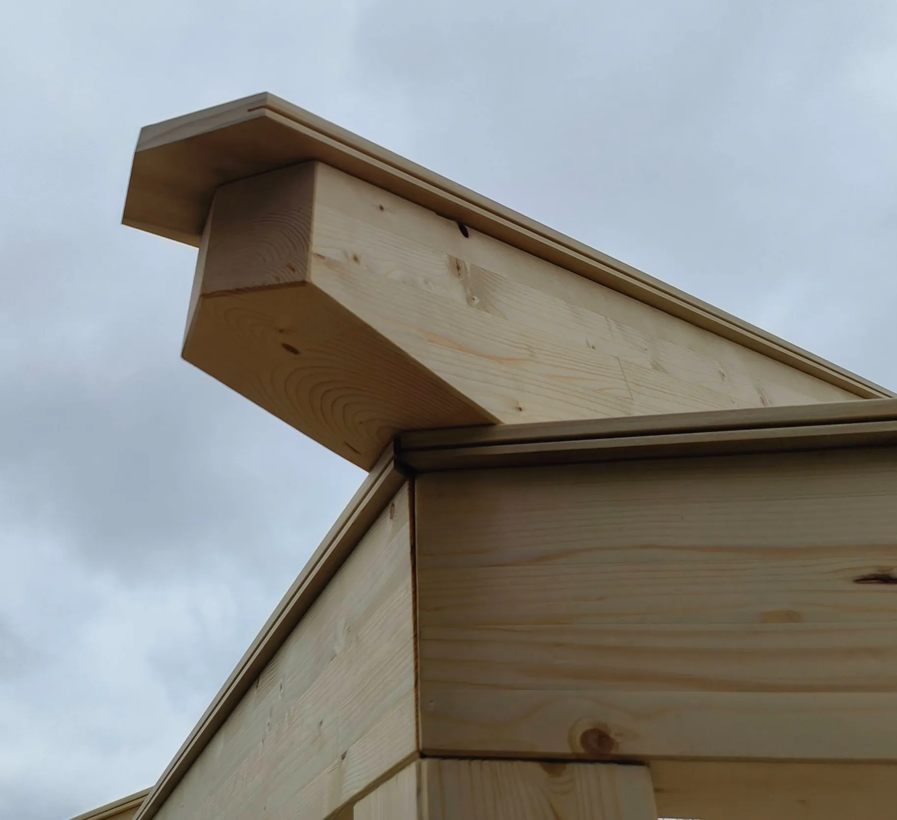 Sparrenende der Pergola mit wetterseitiger Abdeckung aus Accoya-Brettern vor bewölktem Himmel