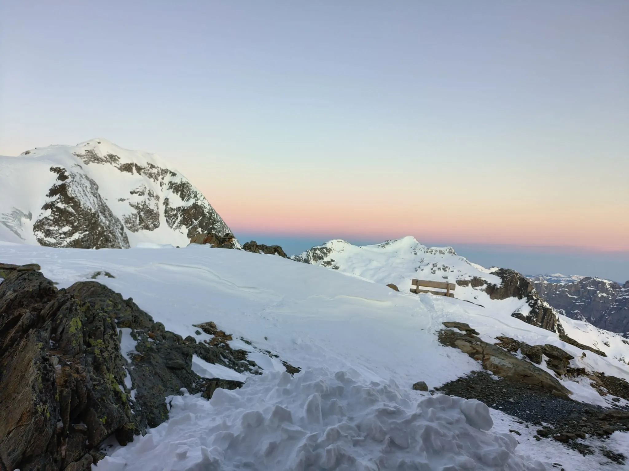 Verschneite Hochgebirgslandschaft mit Sitzbank in der Dämmerung bei der SAC-Hütte Tierbergli