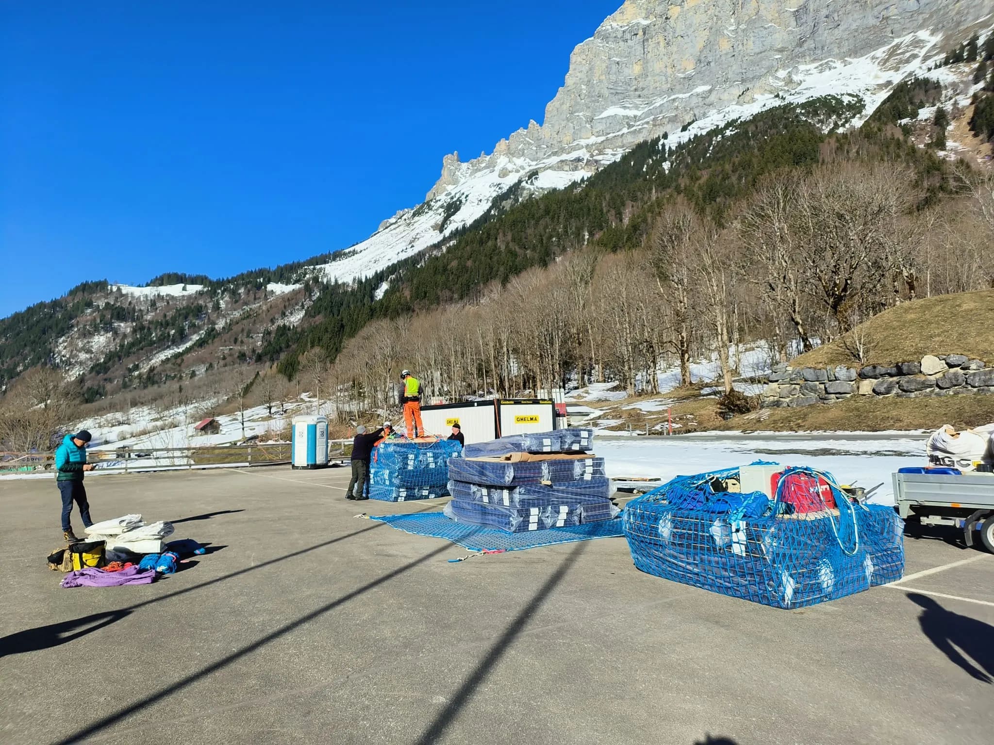 Material in blauen Netzen wird auf dem Parkplatz für den Helikoptertransport zur SAC-Hütte vorbereitet